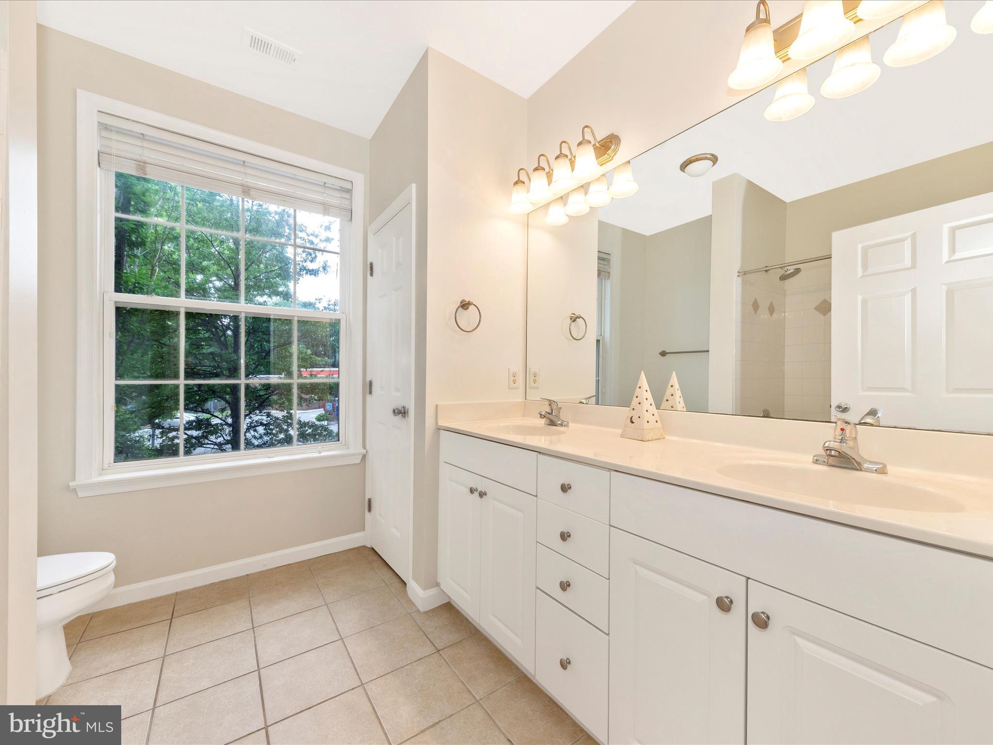7 Booth Street, Unit 201 Gaithersburg, MD 20878 - Photo 26 of 67 a spacious bathroom with a granite countertop sink a toilet a mirror and a window