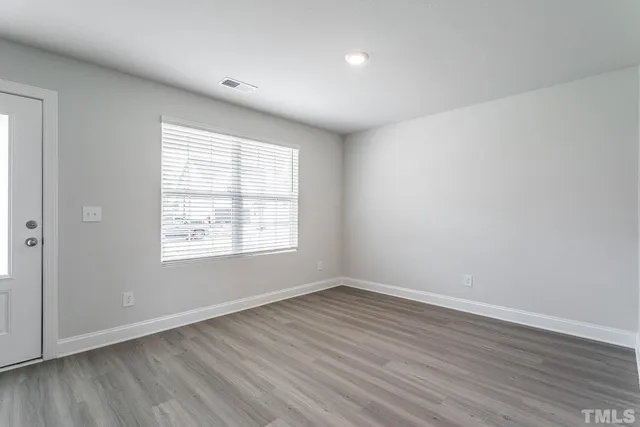 an empty room with wooden floor and window