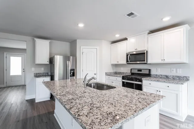 a kitchen with stainless steel appliances granite countertop a sink stove microwave and refrigerator