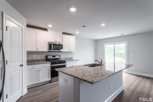 a kitchen with granite countertop stainless steel appliances a stove sink and microwave