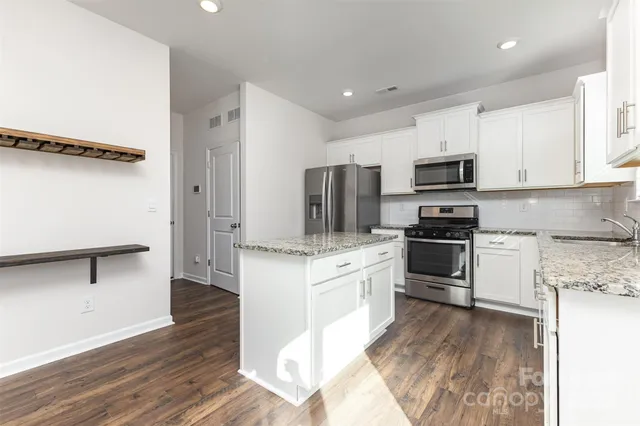 a kitchen with granite countertop a refrigerator stove and microwave