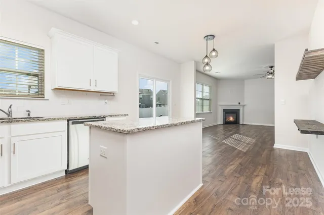 a kitchen with stainless steel appliances granite countertop a sink stove and white cabinets with wooden floor