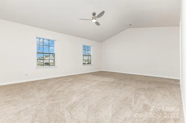 an empty room with windows and ceiling fan