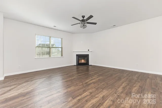 an empty room with wooden floor windows and fireplace