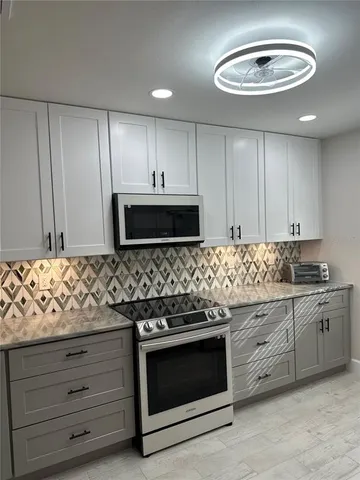 a kitchen with granite countertop white cabinets and stainless steel appliances
