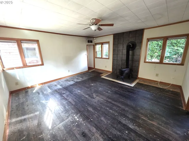 a view of an empty room with a window and wooden floor