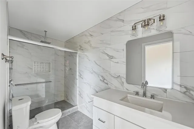 a bathroom with a granite countertop sink toilet a mirror and shower