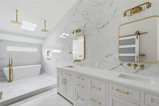 a bathroom with a double vanity sink mirror and bathtub