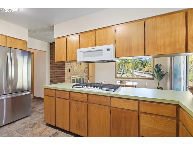 a kitchen with stainless steel appliances granite countertop a sink a refrigerator and a counter top space