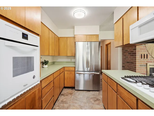 a kitchen with stainless steel appliances granite countertop a refrigerator a stove and a sink with cabinets