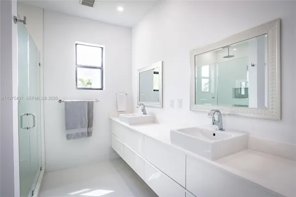 a bathroom with a double vanity sink mirror and next to a window
