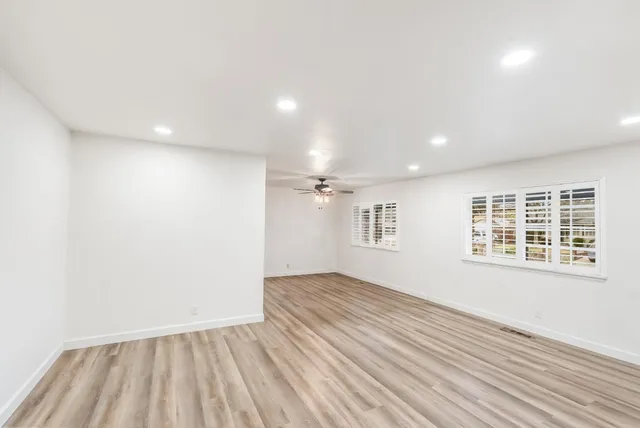 an empty room with wooden floor and windows