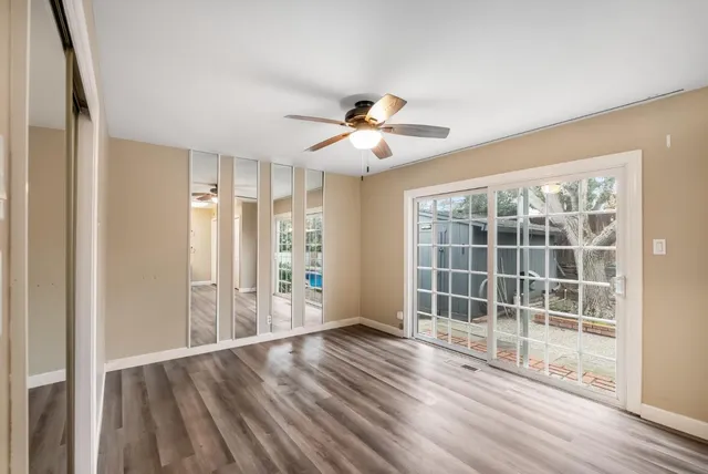 a view of a hallway with wooden floor and a bathroom