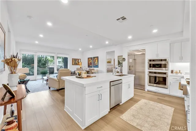 a large white kitchen with a stove a sink a refrigerator and wooden floor