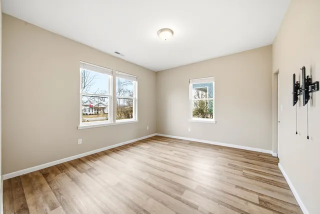 a view of an empty room with window and wooden floor