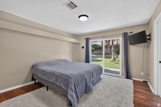 1690 Maplewood Way St. George, UT 84790 - Photo 8 of 17 Spacious secondary bedroom featuring wood-finish flooring, neutral wall finishes, and abundant natural light from sliding glass doors opening to the backyard