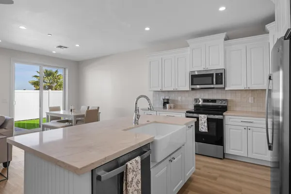 a kitchen with kitchen island granite countertop a sink cabinets and stainless steel appliances