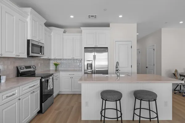 a kitchen with kitchen island granite countertop a sink cabinets and stainless steel appliances
