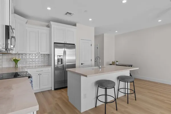 a kitchen with stainless steel appliances a sink a stove a refrigerator cabinets and wooden floor