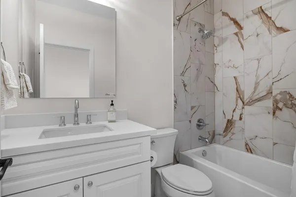 a bathroom with a toilet sink vanity tub and shower