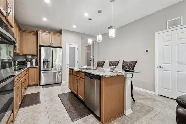 a kitchen with kitchen island granite countertop wooden cabinets and a refrigerator