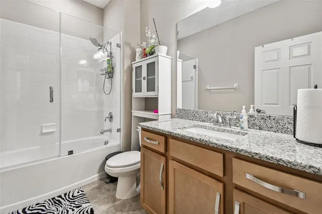 a bathroom with a granite countertop sink a toilet and a mirror