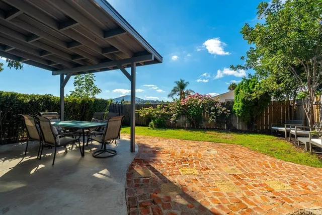 a view of a patio with table and chairs under an umbrella with a small yard