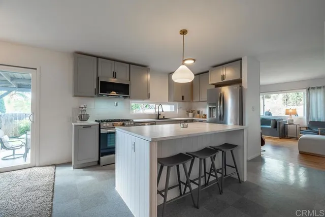 a kitchen with kitchen island granite countertop a sink a stove and a refrigerator