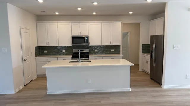 a view of a big room with wooden floor and windows