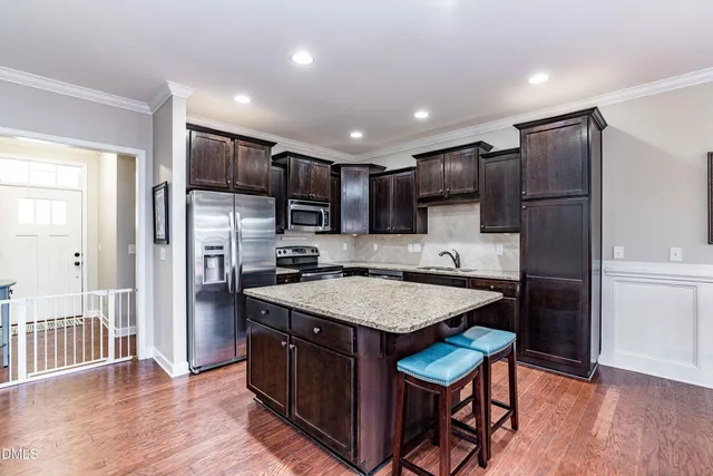 a kitchen with stainless steel appliances granite countertop a refrigerator a stove and a sink
