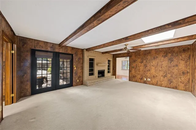 a view of an empty room with a fireplace and windows