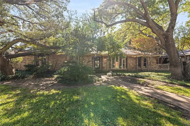 a view of a yard in front of a house with large trees