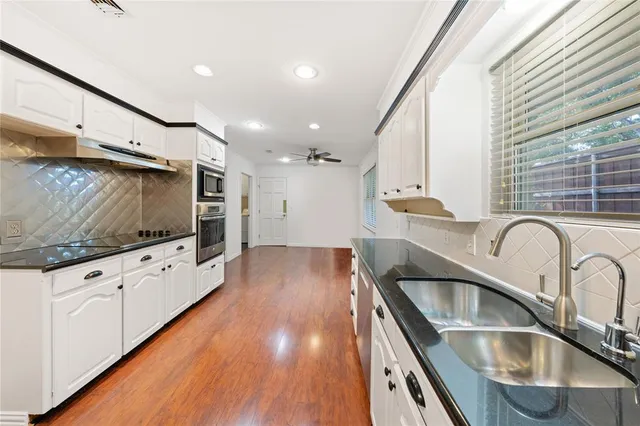 a kitchen with stainless steel appliances granite countertop a sink a stove and a wooden floors