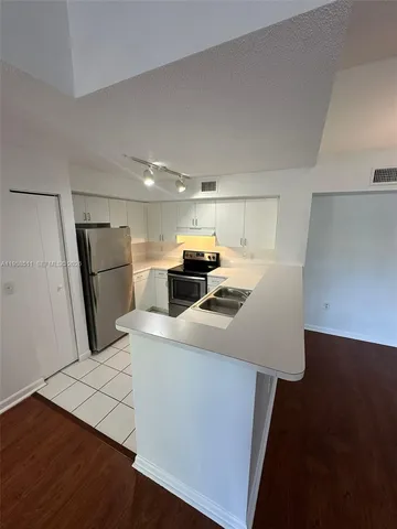 a kitchen with stainless steel appliances a refrigerator a sink a stove and white cabinets