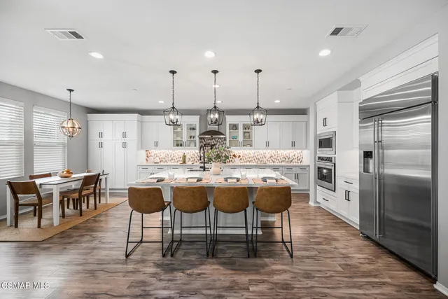 a dining hall with stainless steel appliances kitchen island granite countertop a dining table chairs and granite counter tops