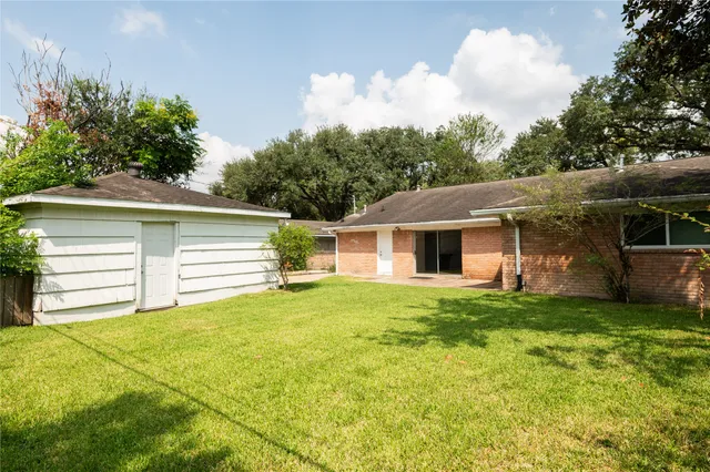 a view of a house with a yard and a large tree