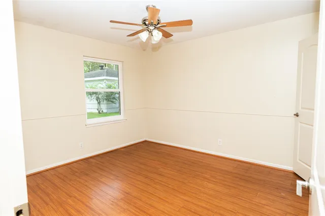 an empty room with a window and a ceiling fan