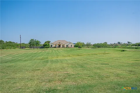 a view of a green field with trees in the background