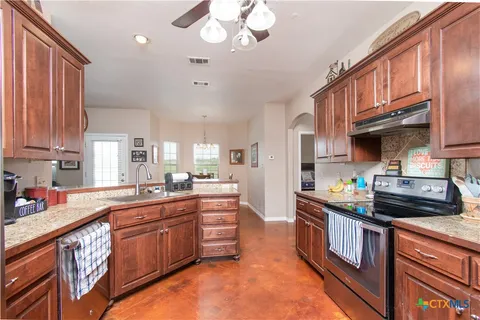 a kitchen with stainless steel appliances granite countertop a stove a sink dishwasher and cabinets with wooden floor
