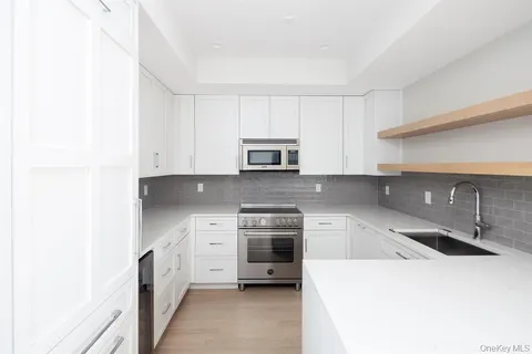 a kitchen with granite countertop white cabinets and stainless steel appliances