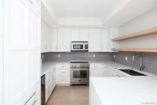 a kitchen with granite countertop white cabinets and stainless steel appliances