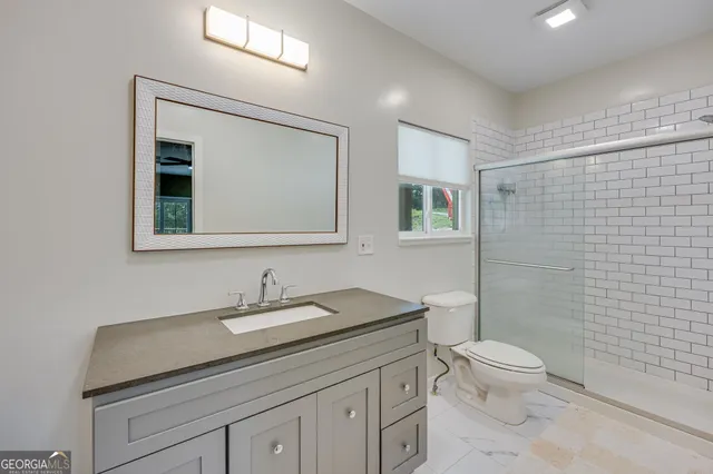 a bathroom with a granite countertop sink a toilet and a mirror