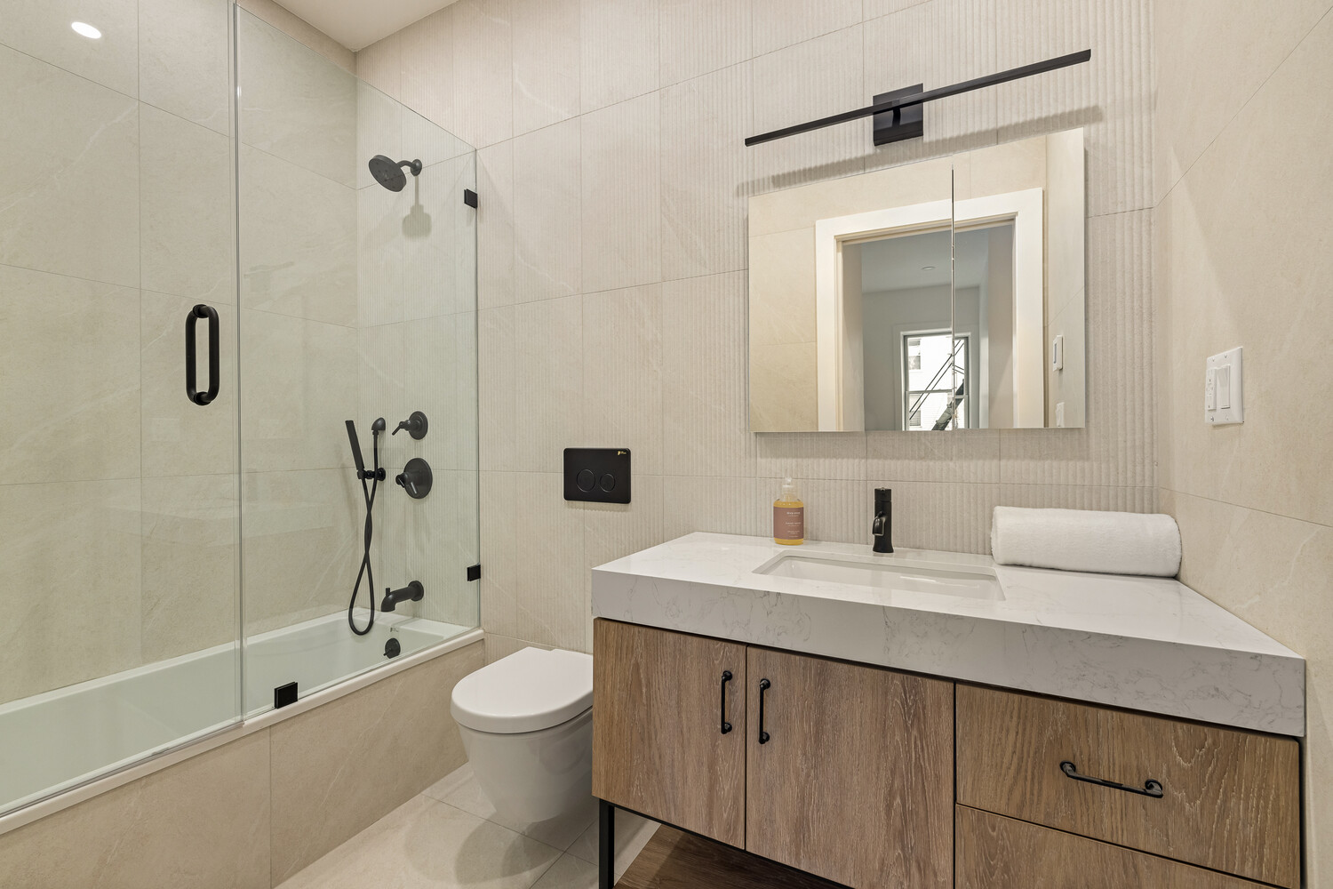 1230 Putnam Avenue, Unit 2 Brooklyn, NY 11221 - Photo 10 of 13 a bathroom with a toilet a sink a mirror a bathtub and shower