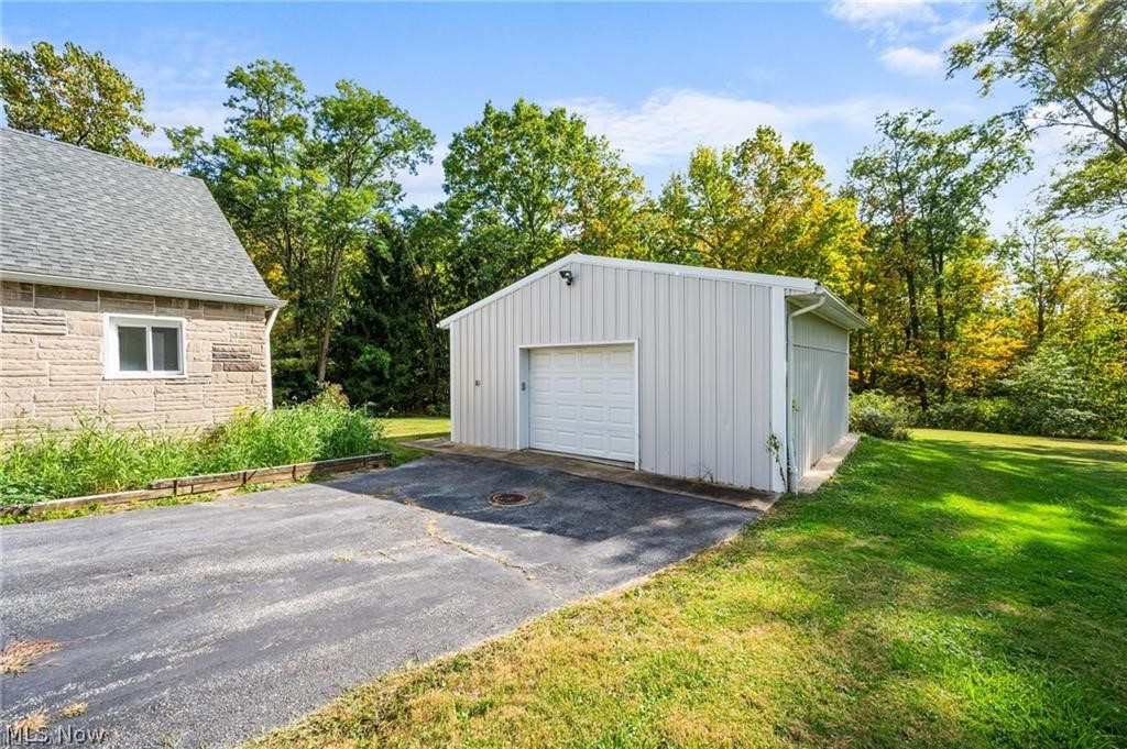 28300 Aurora Road Solon, OH 44139 - Photo 36 of 36 Detached metal utility building with a roll-up door, paved driveway, and surrounding green lawn