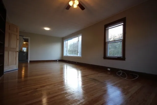 a view of an empty room with wooden floor and a window