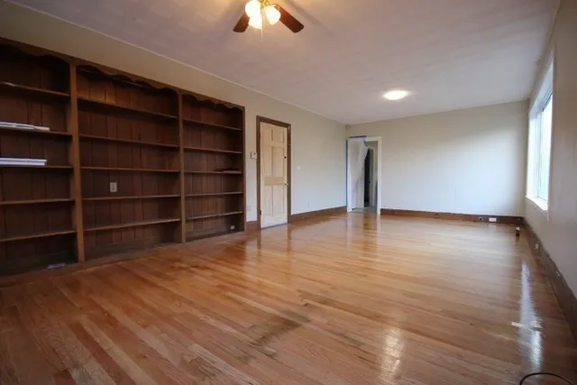 a view of an empty room with a window and wooden floor