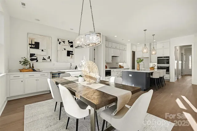 a kitchen with stainless steel appliances kitchen island granite countertop a table chairs and a refrigerator
