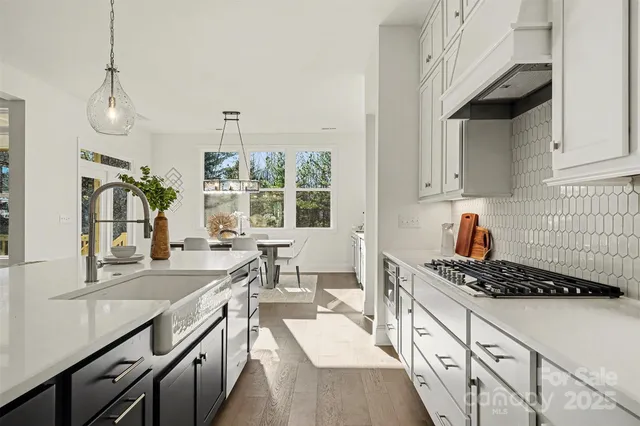 a open kitchen with stainless steel appliances granite countertop a stove a sink dishwasher a dining table and chairs with wooden floor