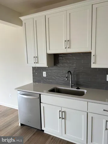 a kitchen with white cabinets and sink