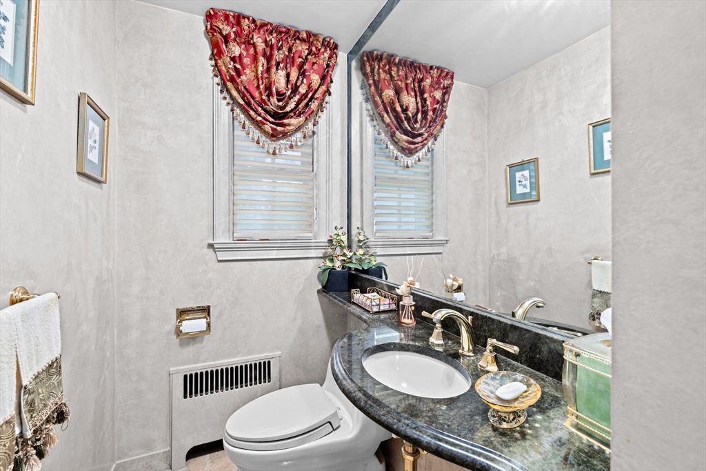443 Chestnut Street Newton, MA 02468 - Photo 18 of 28 a bathroom with a granite countertop toilet a sink and a mirror